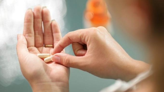 Žena s ADHD drží ritalín pilulky v dlani